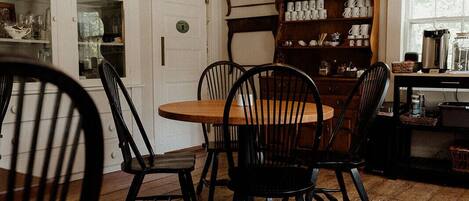 A dining area with a wooden table and chairs, a chandelier, and a cabinet with dishes.