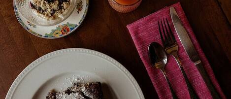 A wooden table with a plate of food, a glass of drink, and cutlery on a napkin.