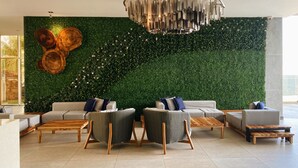 A modern living room with a green wall, two sofas, wicker chairs, and a wooden coffee table.