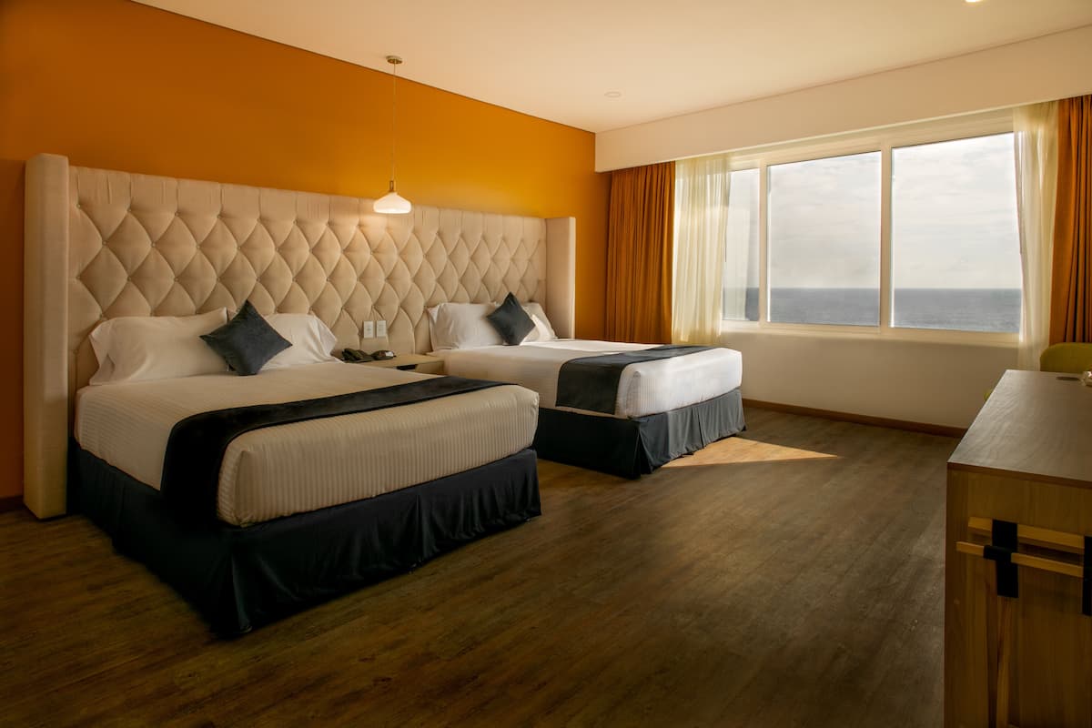 Une chambre d’hôtel avec deux lits, une grande fenêtre donnant sur un beau paysage et un plancher en bois.