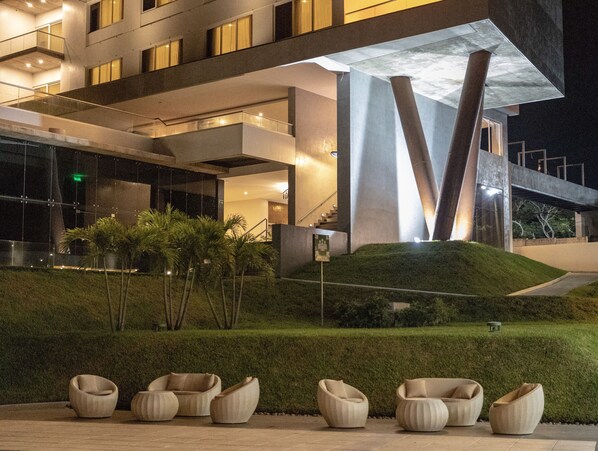 A modern building with a glass facade, outdoor seating, and a well-maintained lawn.