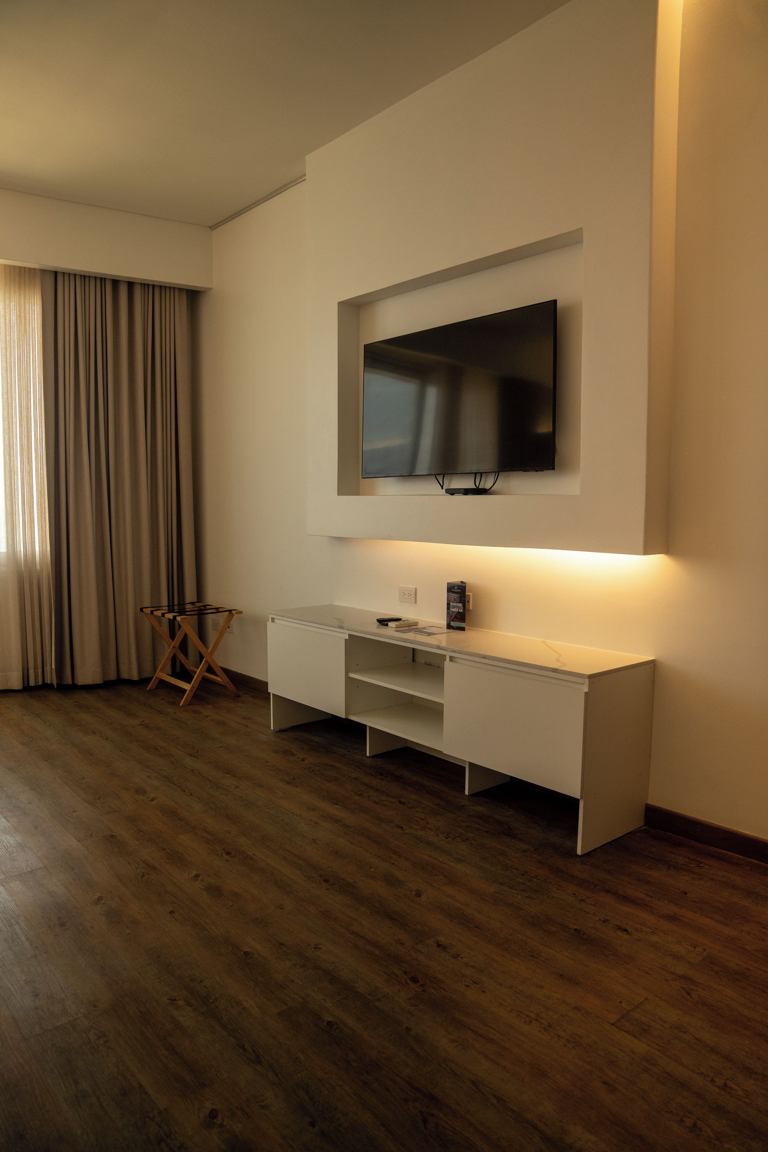 A modern room with a flat-screen TV mounted on the wall, a white console table, and a wooden floor.