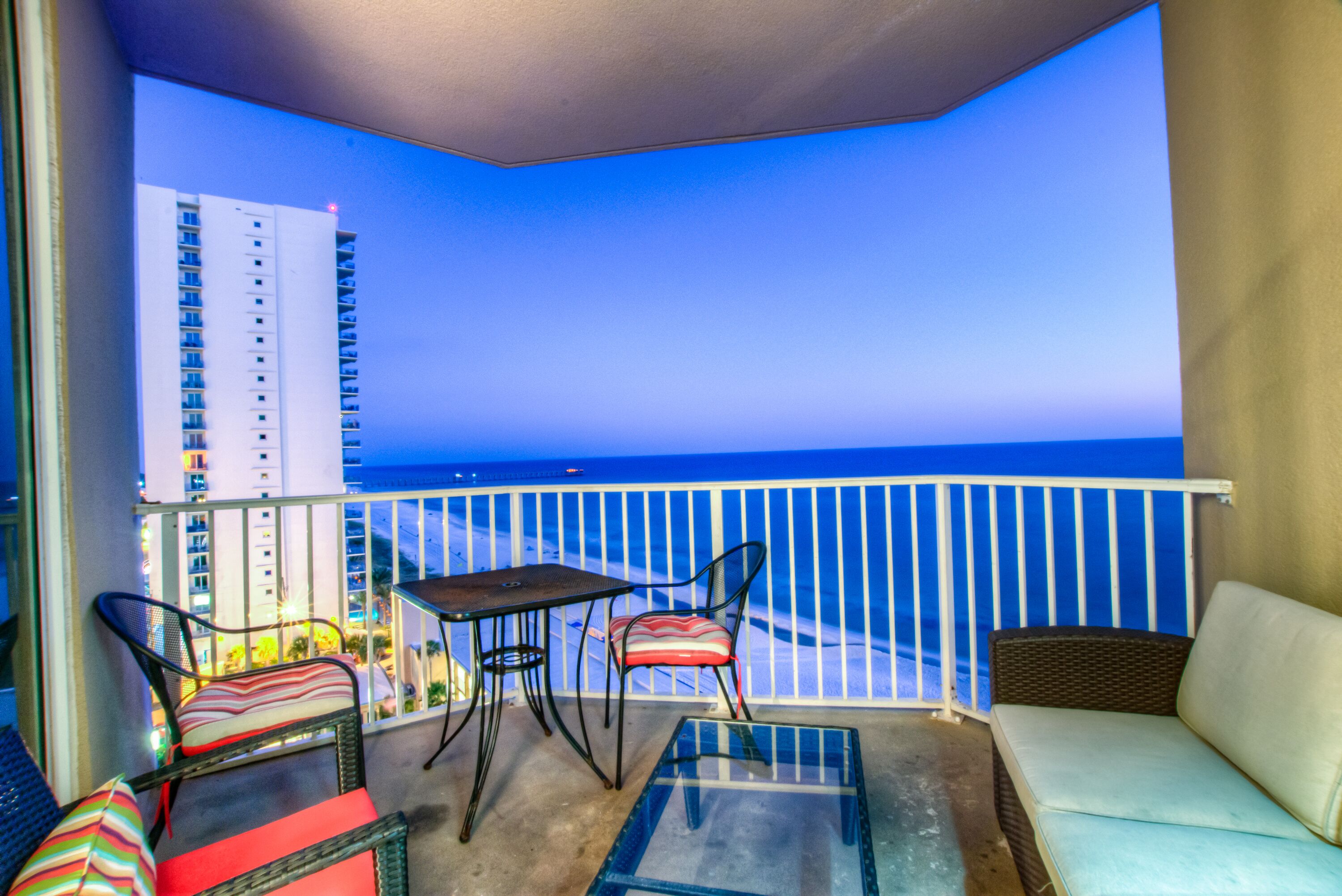 A balcony with a glass table, two chairs, and a sofa.
