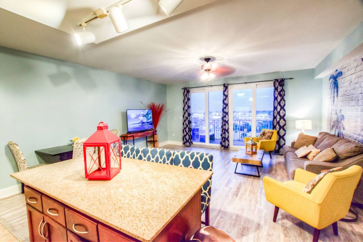 A living room with a kitchen area, a dining table, and a television.
