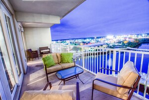 En balkon med sofa, stole og et glasbord.