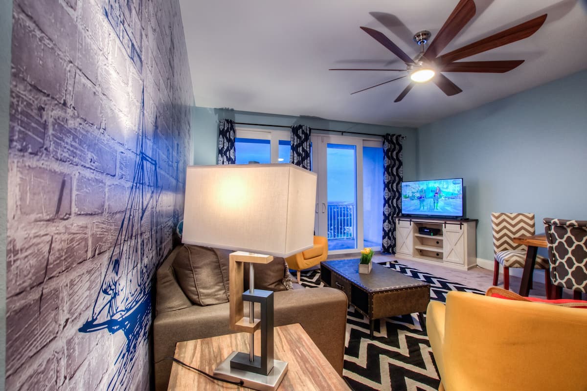 A modern living room with a sofa, a coffee table, a TV, and a ceiling fan.