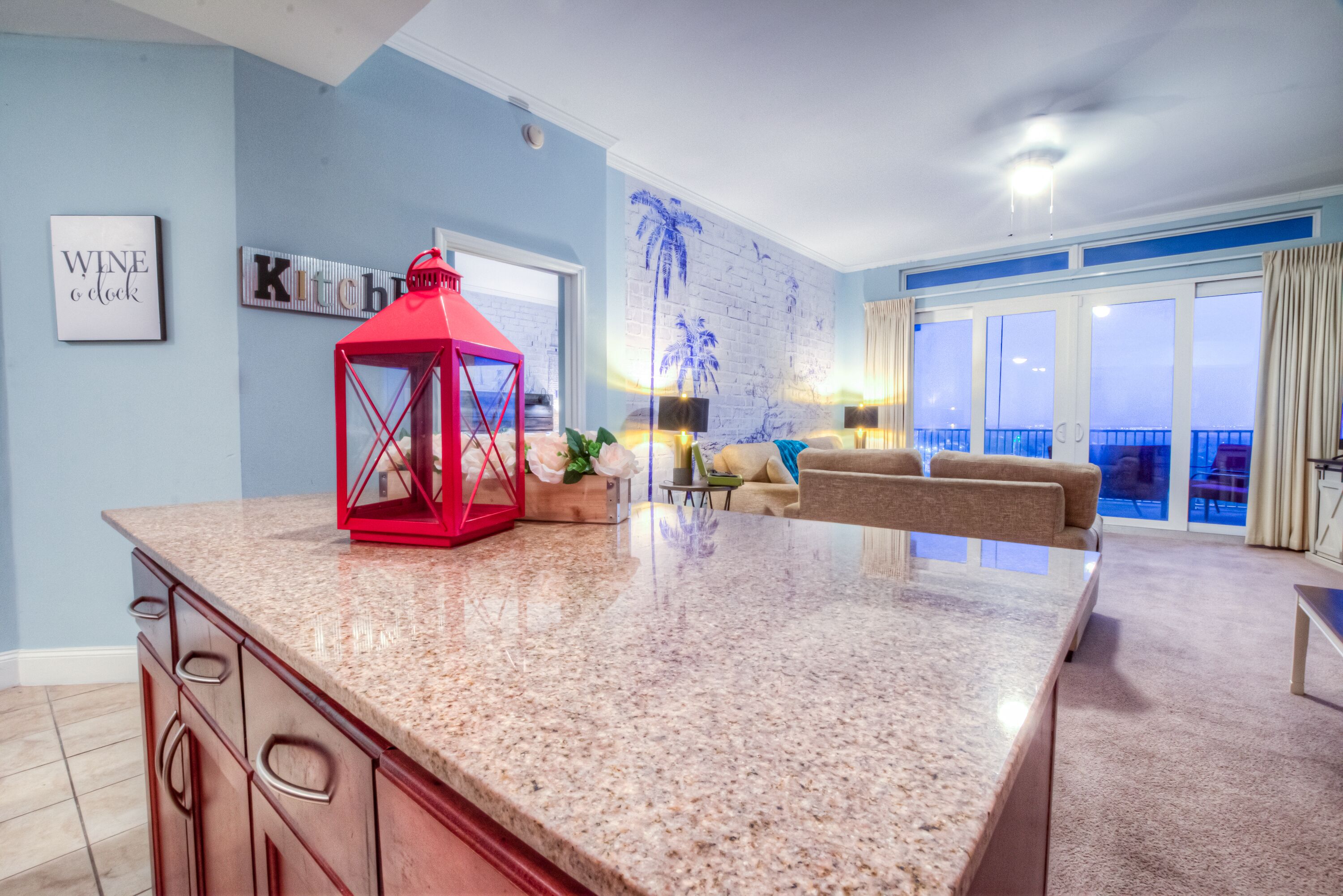 A modern living room with a kitchen island, a red lantern, and a large window with a view.