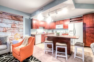 Une cuisine moderne avec des meubles en bois, un réfrigérateur blanc et un coin bar équipé de tabourets.