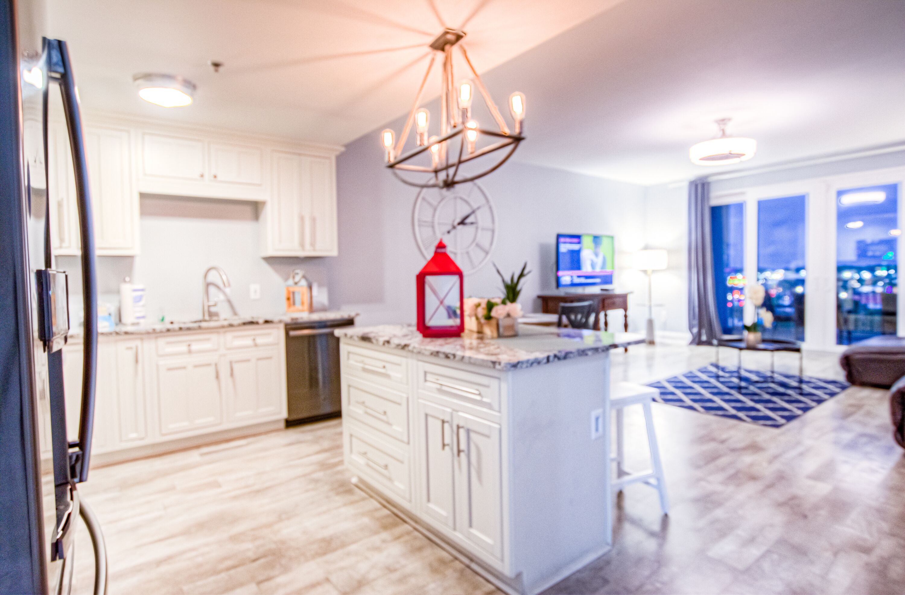 A modern kitchen with white cabinetry, a central island, and a red lantern.