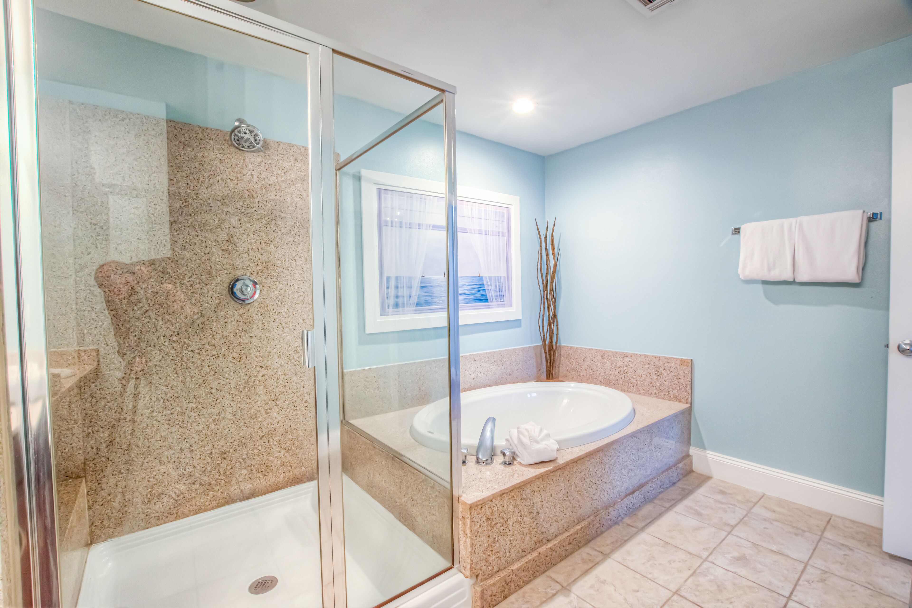 A bathroom with a glass-enclosed shower, a freestanding bathtub, and a window with a view.