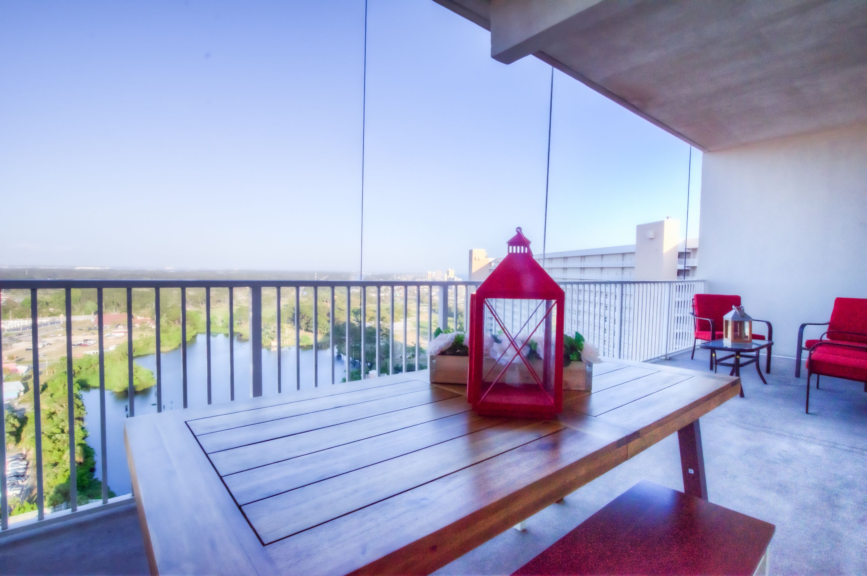 A balcony with a wooden table, red chairs, and a red lantern.