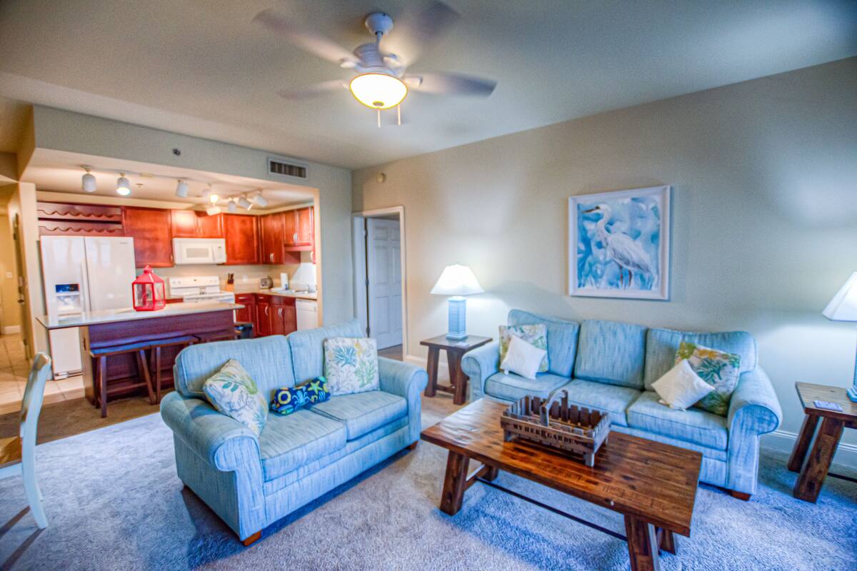 A living room with two sofas, a coffee table, and a kitchen in the background.