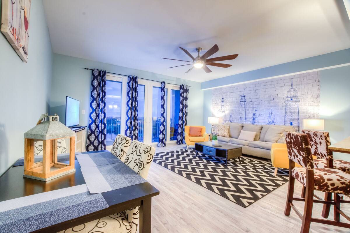 A modern living room with a sofa, a dining table, and a patterned rug.