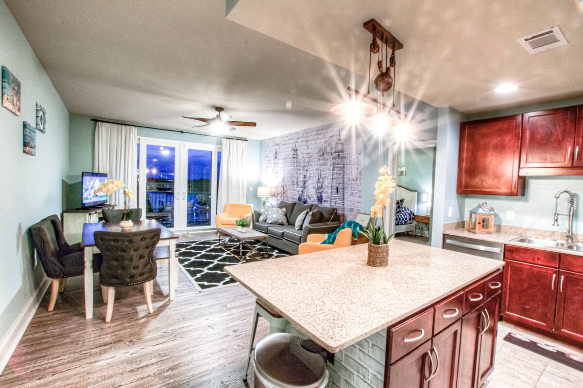 A modern kitchen with granite countertops, wooden cabinets, and a dining area with a table and chairs.