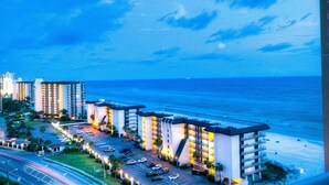 A hotel with multiple floors, a parking lot, and a view of the ocean. - Grand Panama by Aneliya's Rentals (Panama City Beach)