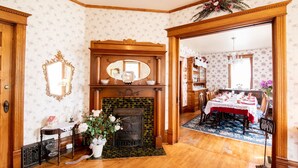 A room with a fireplace, a dining area, and a mirror above it. - Garden Gate BnB (Sturgeon Bay)
