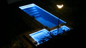 A rectangular swimming pool at night, illuminated by a single light source. - Casa Alta Hotel Boutique Solo Adultos (Villa Carlos Paz)