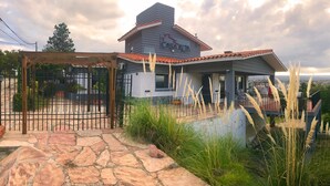 A modern house with a covered patio, stone pathway, and surrounding greenery. - Casa Alta Hotel Boutique Solo Adultos (Villa Carlos Paz)