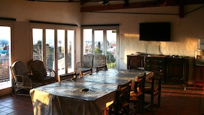 A dining area with a large table, chairs, and a TV mounted on the wall. - Casa Alta Hotel Boutique Solo Adultos (Villa Carlos Paz)