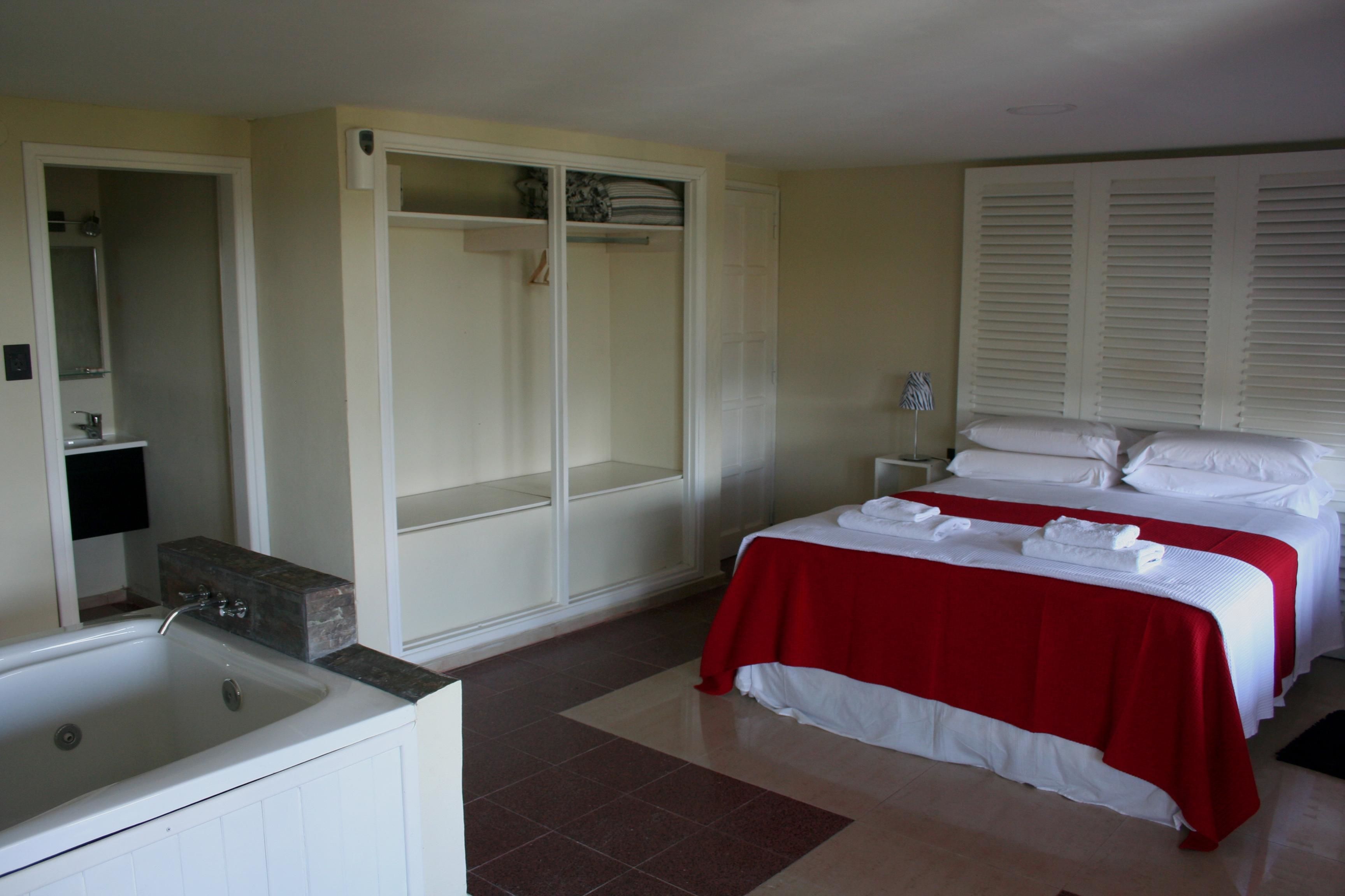 Une chambre d’hôtel avec un lit, une salle de bain avec une baignoire et un dressing.
