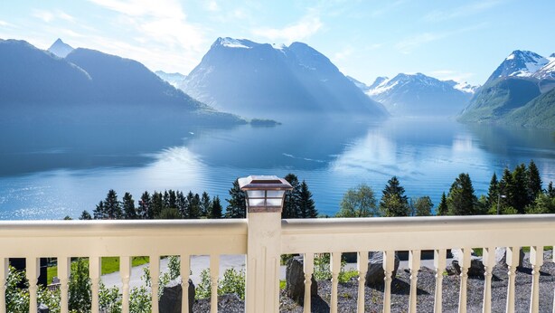 Un balcon donnant sur un lac paisible, entouré de montagnes.