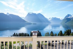 A balcony with a view of a calm lake surrounded by mountains. - Spectacular Norwegian Fjord with unbeatable view, sauna and hot tub (Sæbø)