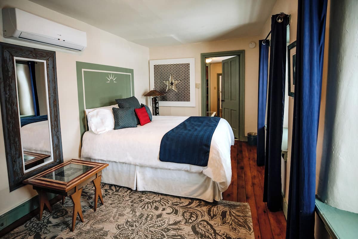 A bedroom with a bed, a mirror, a table, and a patterned rug.