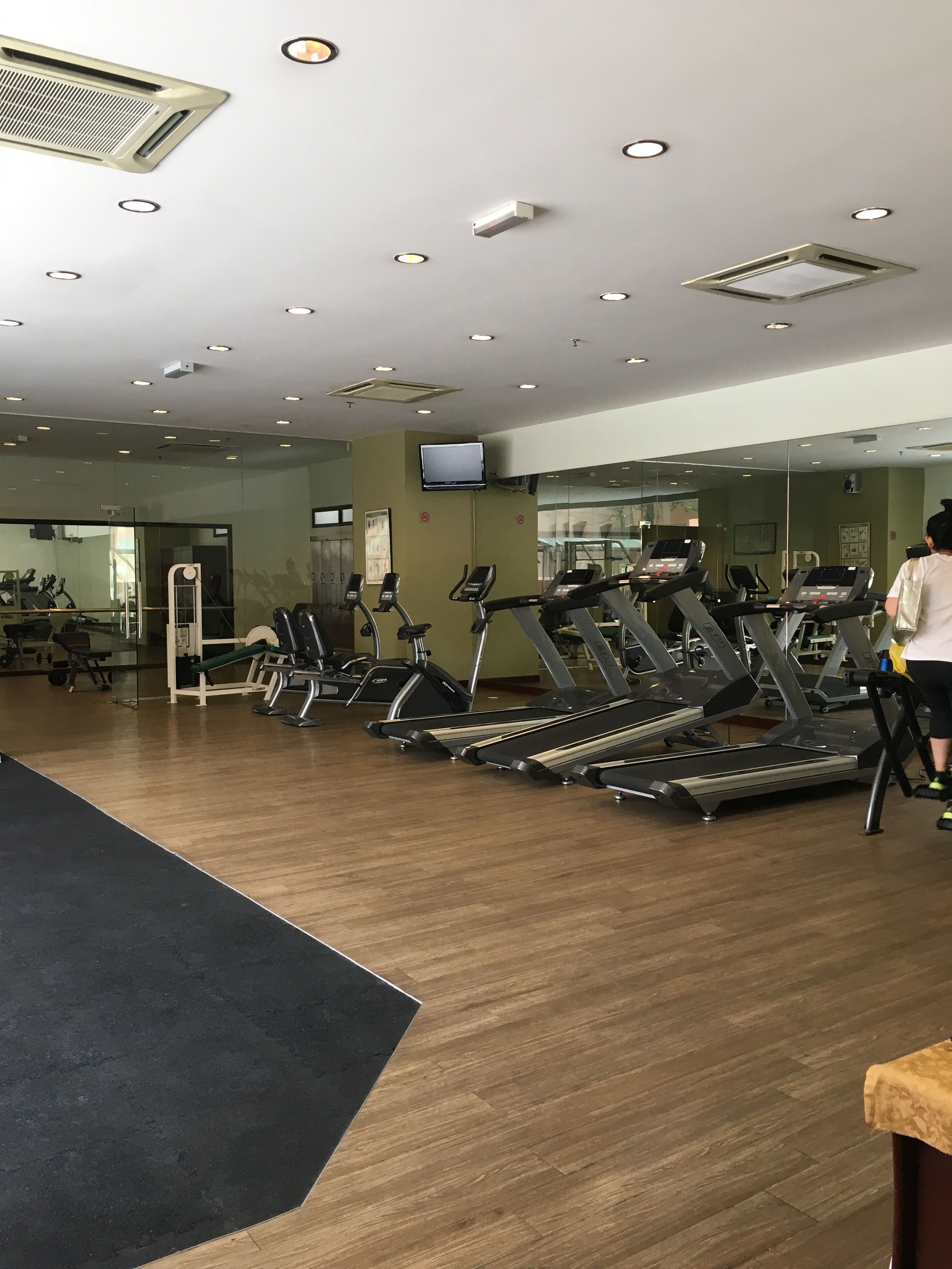 A gym with multiple treadmills, exercise equipment, and a television mounted on the wall.