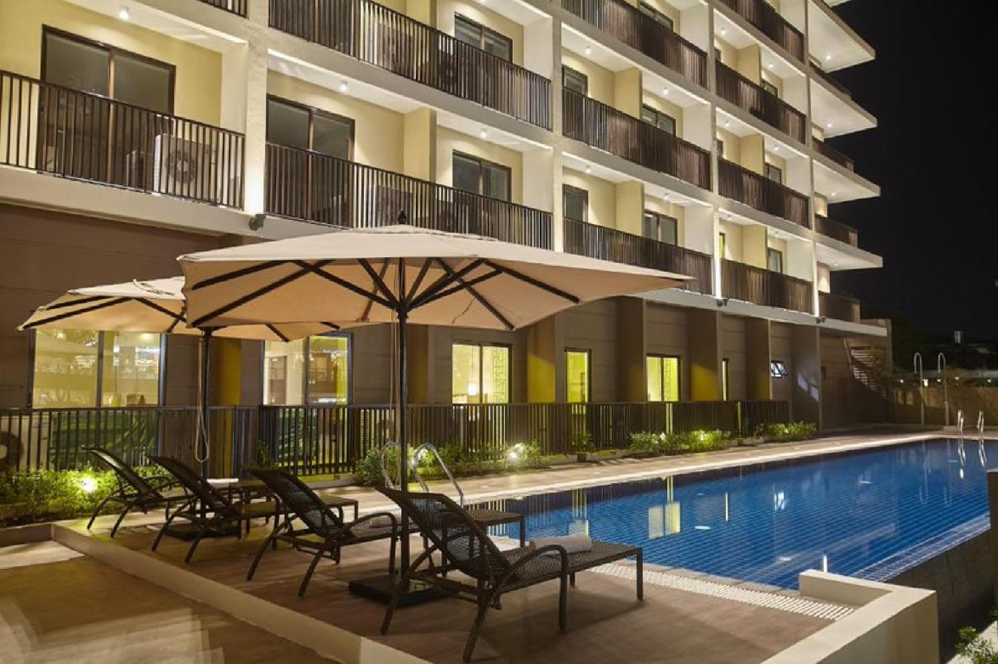 A multi-story hotel with a swimming pool, outdoor seating, and balconies.