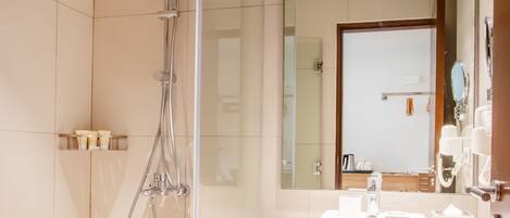 A modern bathroom with a glass-enclosed shower, a white sink, and a large mirror.