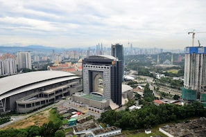 A large stadium with a distinctive arch structure, surrounded by high-rise buildings and construction cranes. - Super Star Icon Mont Kiara Kuala Lumpur (Kuala Lumpur)