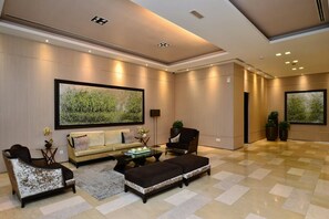 A spacious lobby with a checkered floor, a sofa, armchairs, a coffee table, and two large paintings on the walls. - Super Star Icon Mont Kiara Kuala Lumpur (Kuala Lumpur)