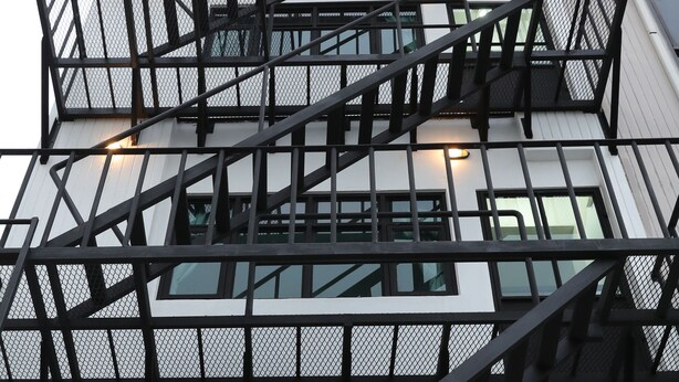 A multi-story building with a prominent external staircase and large windows.