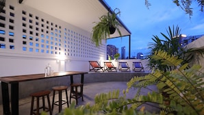 An outdoor seating area with a wooden table and chairs, a white lattice wall, and potted plants.