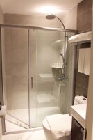 Un baño moderno con ducha de vidrio, inodoro y lavamanos.