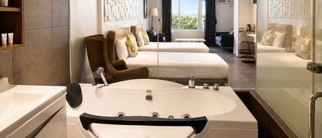 Ein modernes Hotelzimmer mit einer großzügigen Badewanne, zwei Betten, einer Sitzecke und Blick ins Freie.