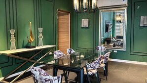 Een vergaderruimte met een glazen tafel, stoelen met een gestreept bekleding, een decoratieve lamp en een wandairconditioner.