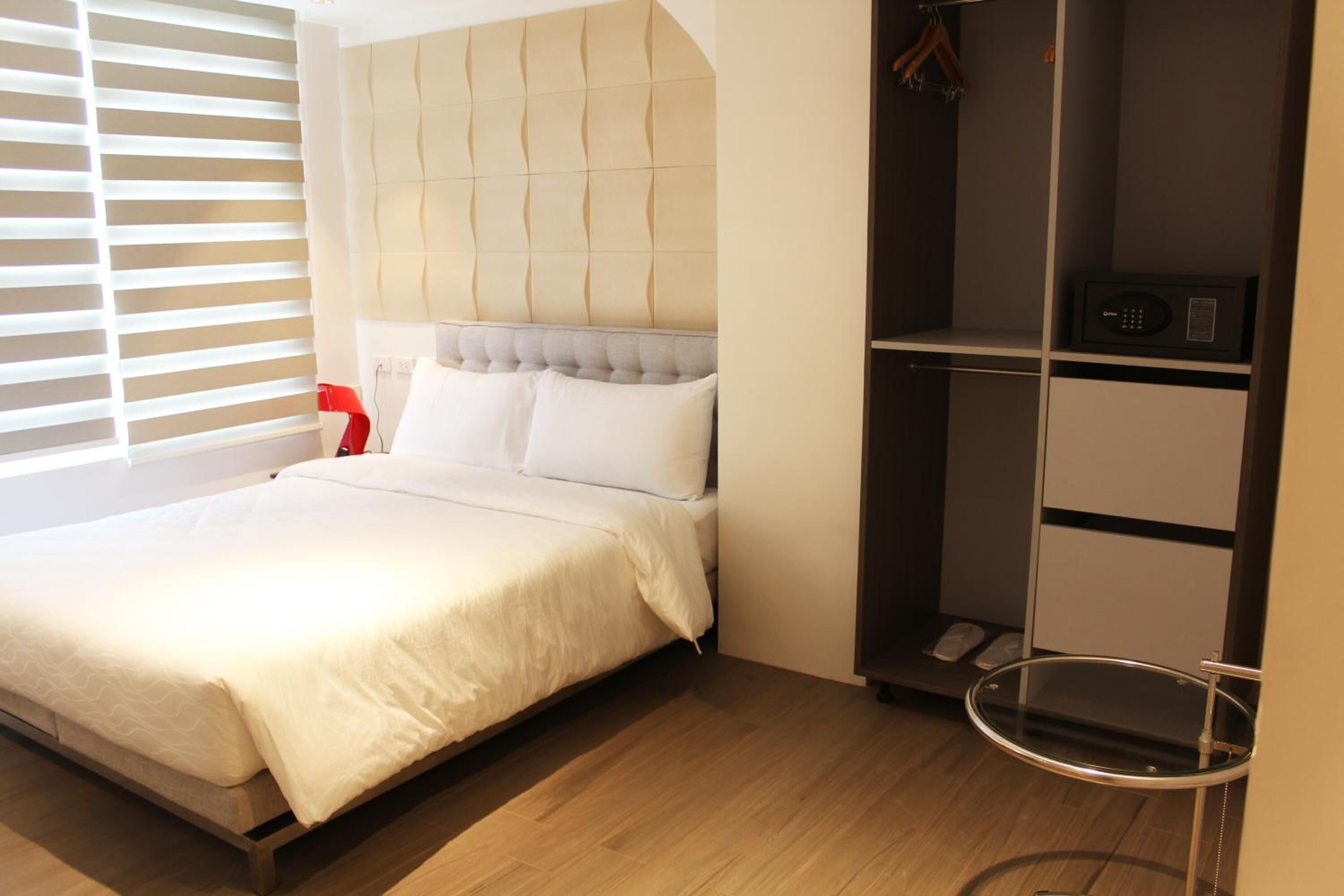 A modern bedroom with a bed, a built-in wardrobe, and a bedside table.