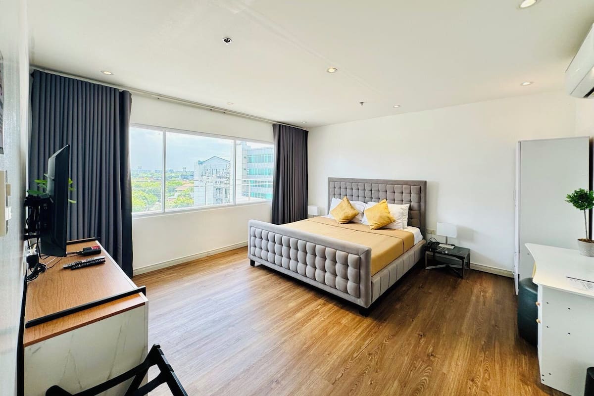 Een moderne hotelkamer met een groot bed, een bureau en uitzicht op de stad.