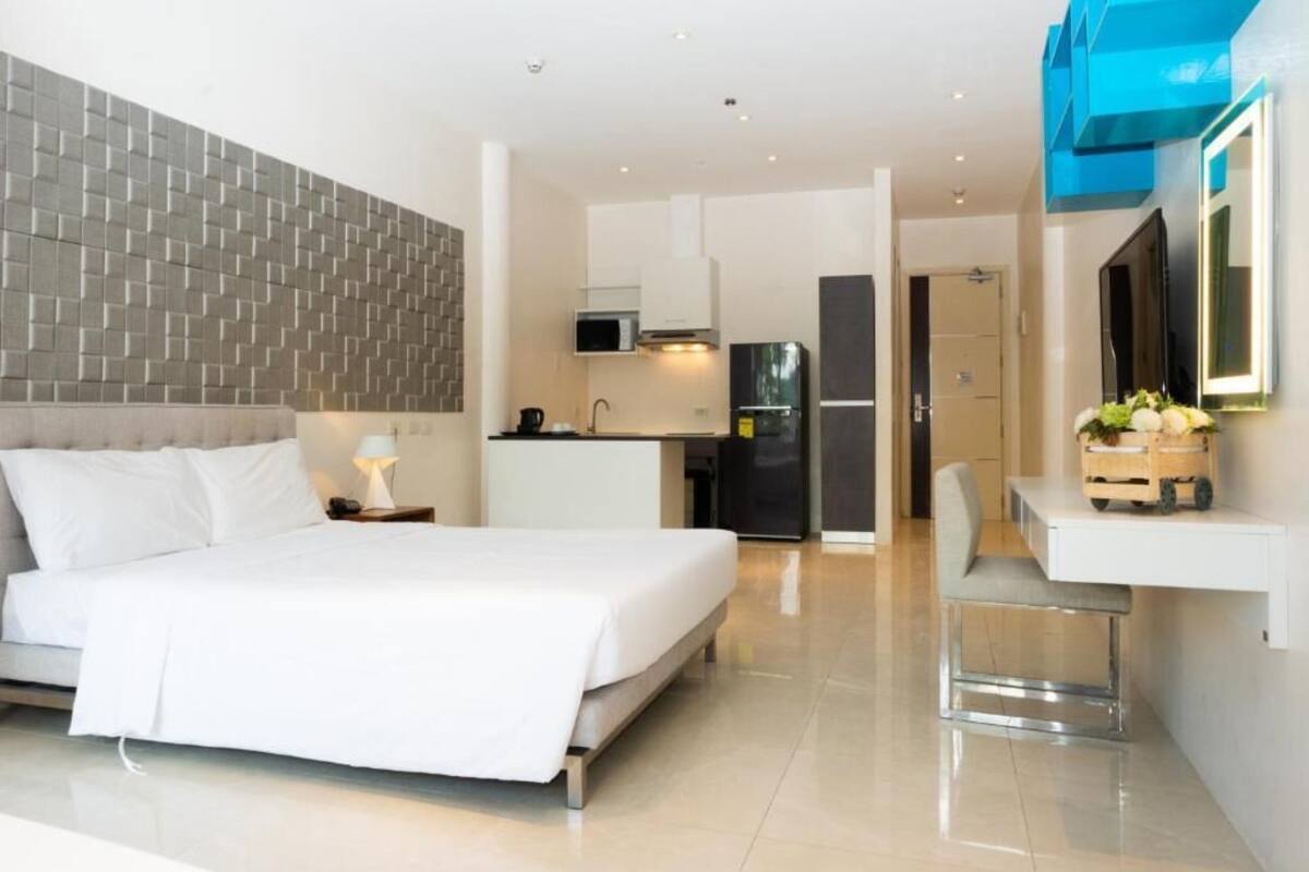 Een moderne hotelkamer met een groot bed, een kitchenette en een eethoek.