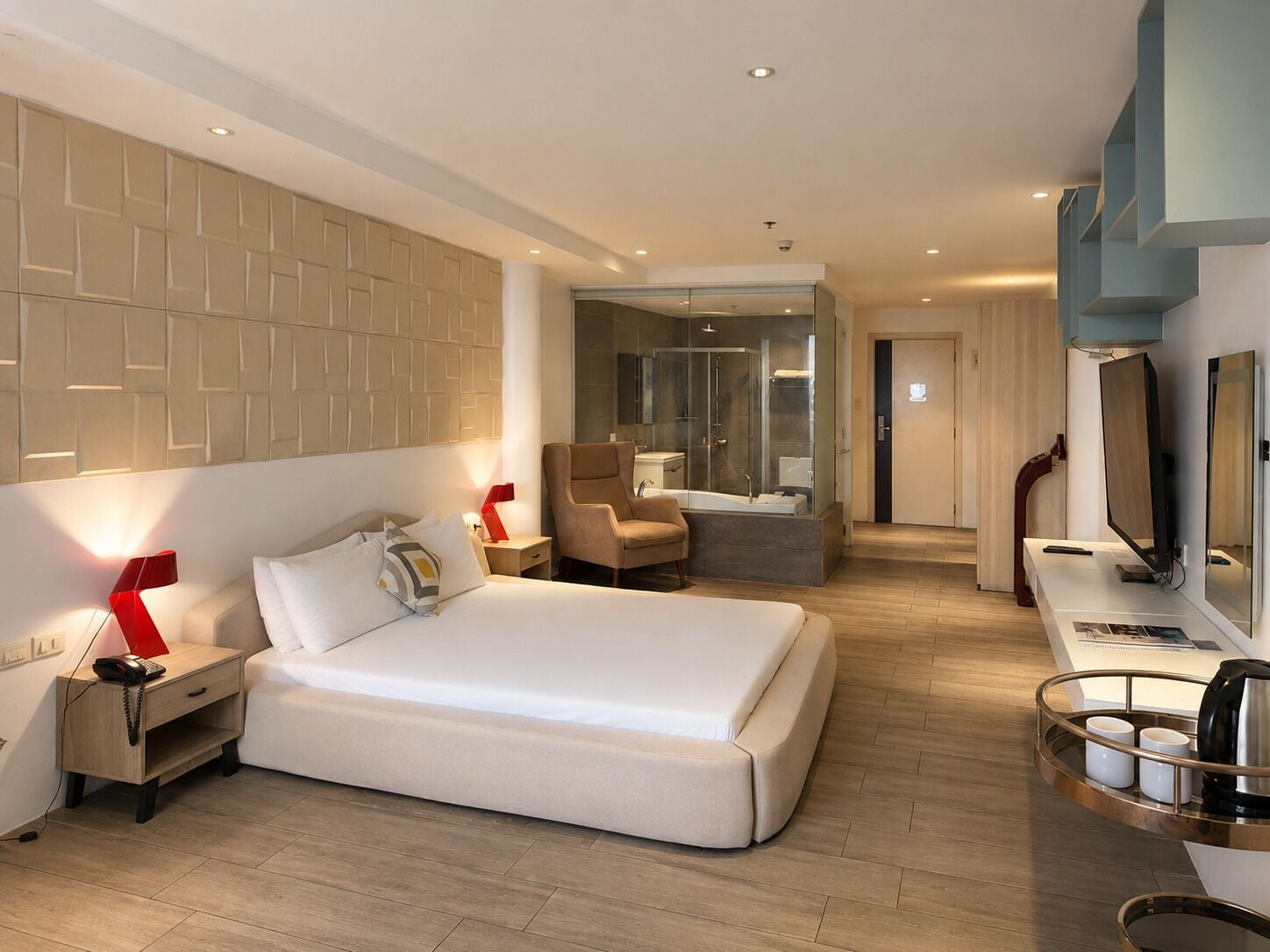 Une chambre d’hôtel moderne dotée d’un grand lit, de tables de chevet, d’un bureau avec une chaise, d’une télévision et d’une salle de bain avec une douche à parois de verre.