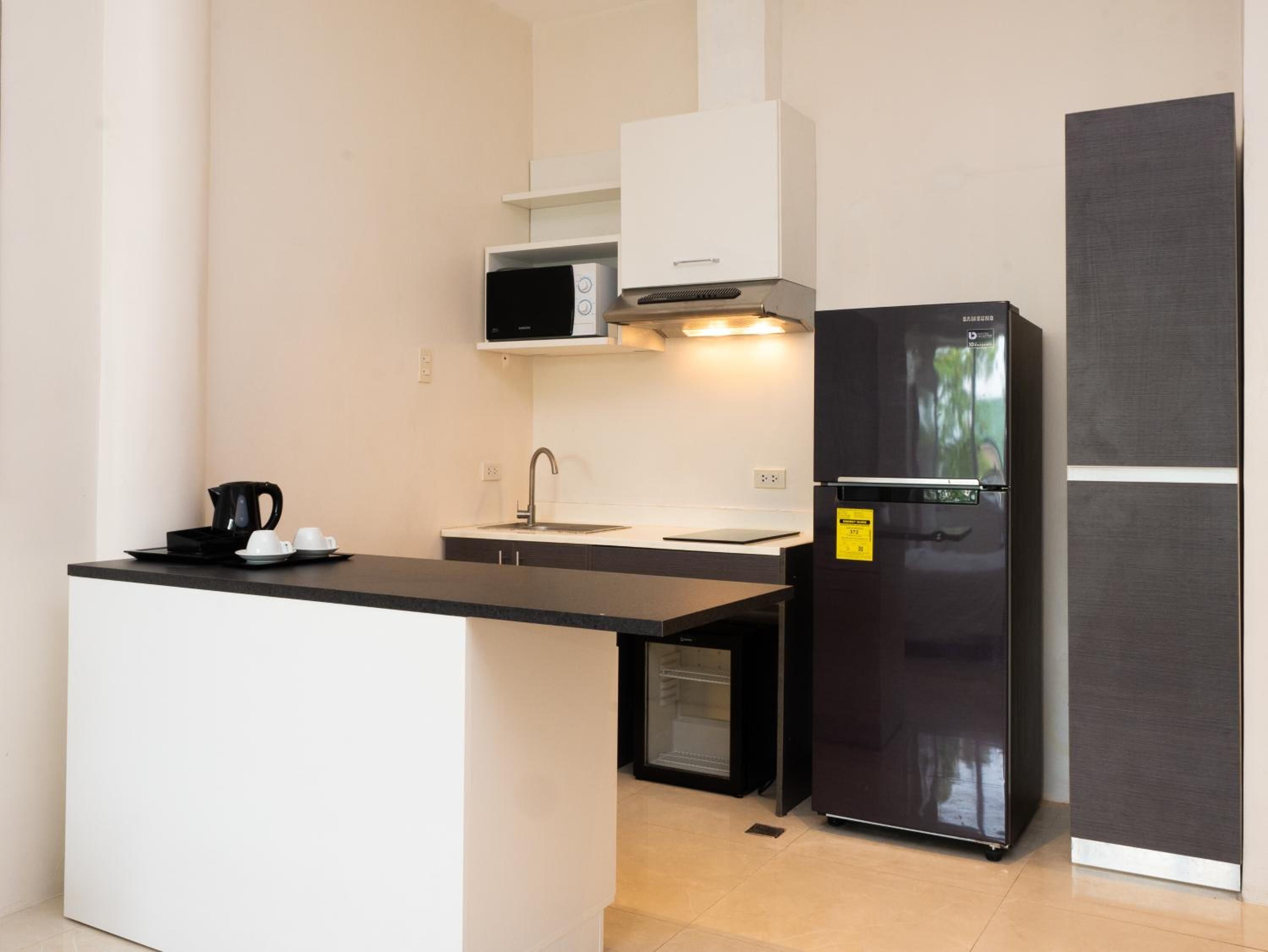 A compact kitchen with a black refrigerator, a microwave, and a coffee maker on the counter.