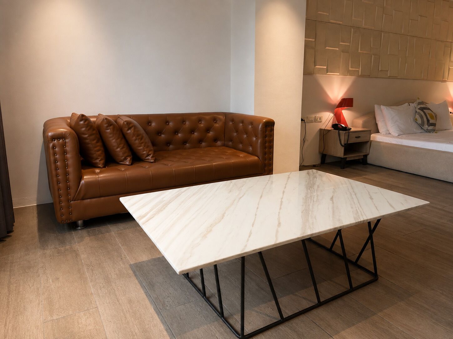 A brown leather sofa with a marble coffee table in a modern living room with a wooden floor.