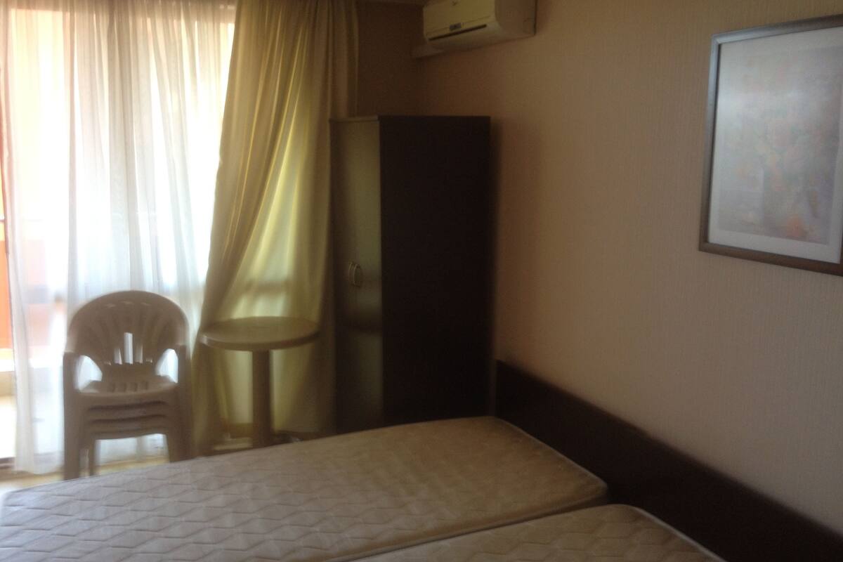 Une chambre d’hôtel avec deux lits, une chaise, une armoire et un tableau encadré au mur.