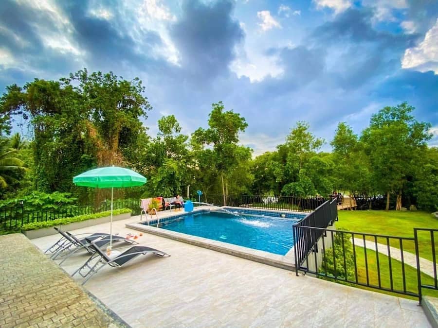 Una piscina al aire libre, sombrillas, sillones reclinables de piscina