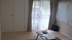 Una habitación amplia con un gran ventanal, un ventilador de techo y una mesa con una silla.
