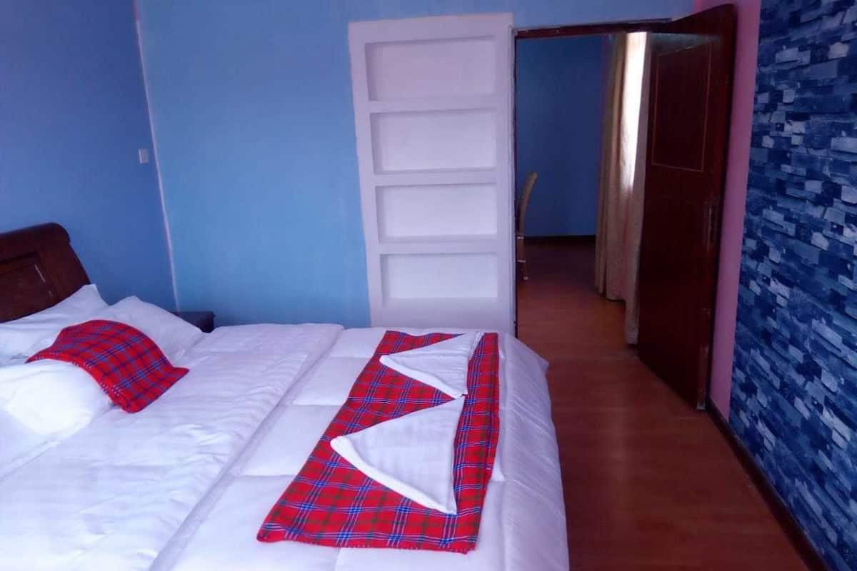 Habitación de hotel con una cama, un armario y un baño visible a través de una puerta abierta.