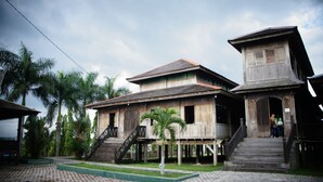A traditional wooden house with a tiled roof, a staircase leading to the entrance, and a small porch area. - Houseboat Bee Kelotok (Kumai)
