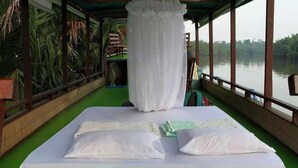 A room with a bed, a canopy, and a view of a body of water. - Houseboat Bee Kelotok (Kumai)