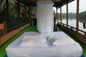 A room with a bed, a canopy, and a view of a body of water.